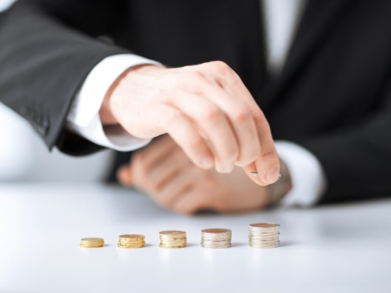 Un homme d'affaire faisant des petites piles de pièces de monnaies.