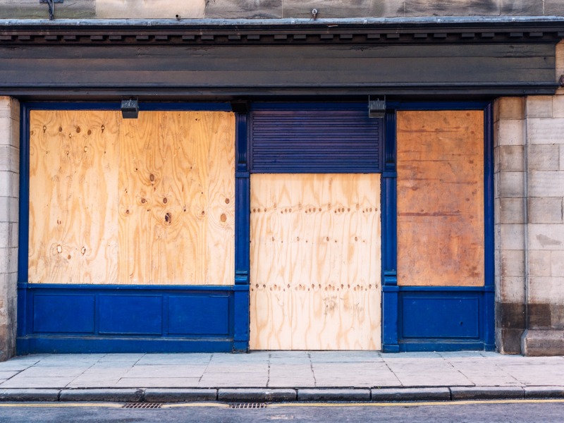 Un magasin dont les vitres ont été remplacées par du bois car il a fait faillite.