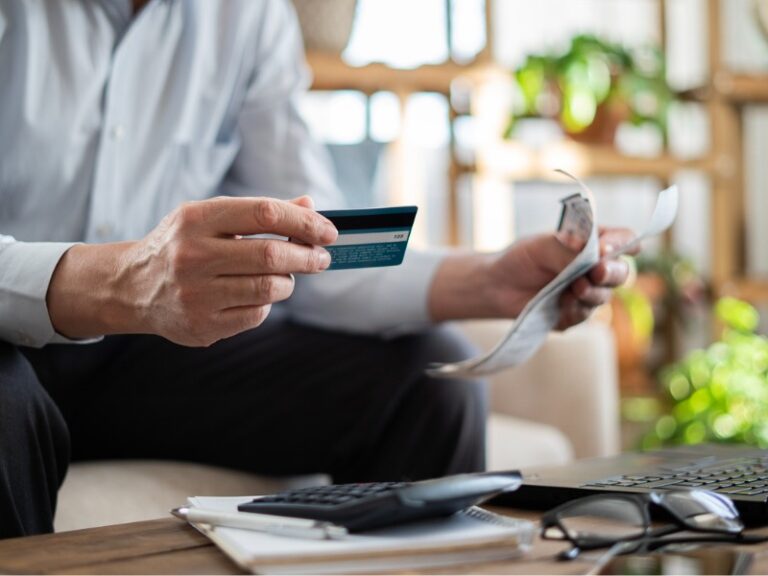 Un homme âgé en gros plan paie ses factures avec une carte de crédit.