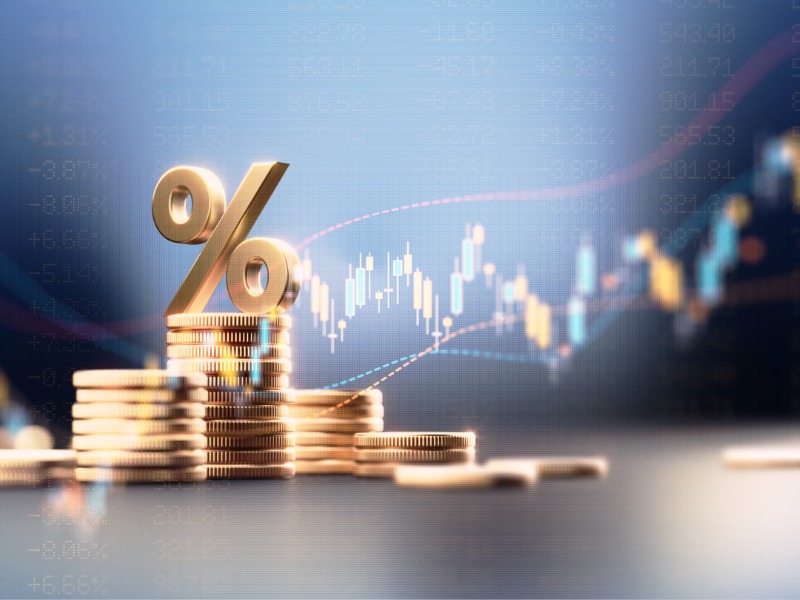 Signe de pourcentage au-dessus des piles de pièces avant le graphique financier bleu.