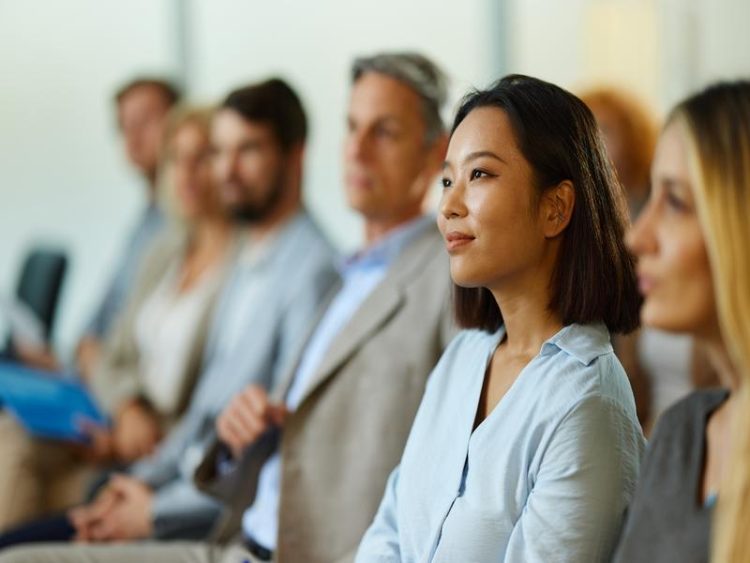 Femme d’affaires chinoise souriante assistant à un séminaire avec ses collègues.