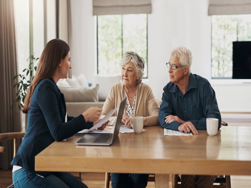 Conseillère échangeant avec un couple de seniors autour d’un ordinateur, illustrant la préparation de la retraite.
