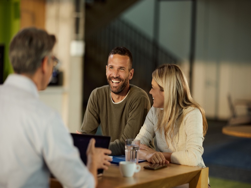 Conseiller discutant avec un couple, représentant la gestion patrimoniale et le conseil personnalisé.