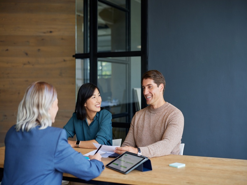 Conseiller échangeant avec un couple dans un cadre détendu, illustrant la confiance et la relation client.