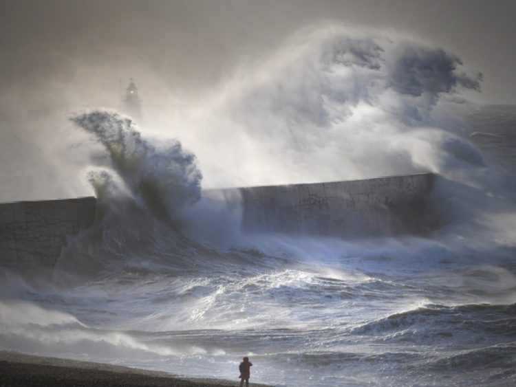 Tempête maritime avec des vagues spectaculaires s’écrasant contre une digue.