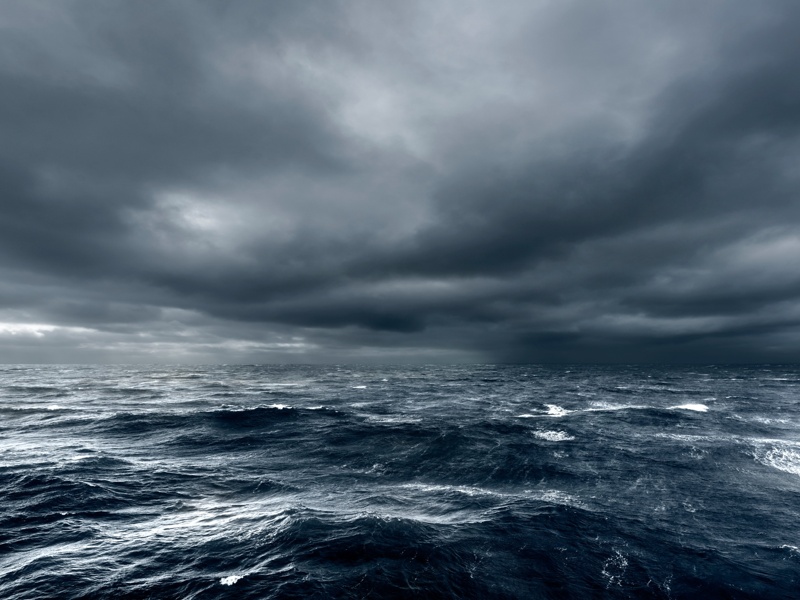 Océan agité sous un ciel sombre annonçant une tempête imminente.